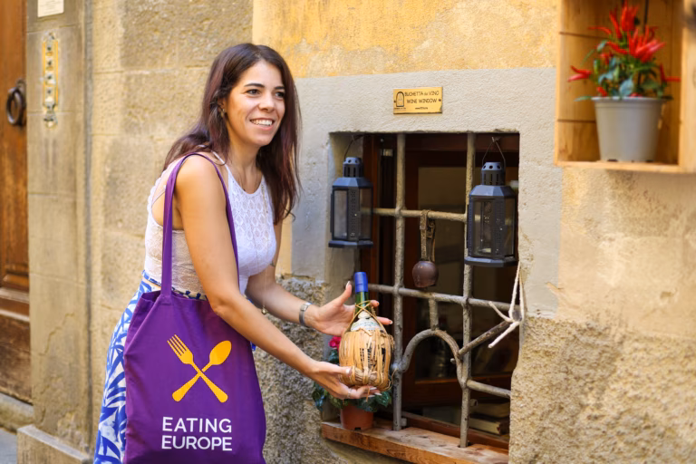 A guide receiving wine through a Florence wine window