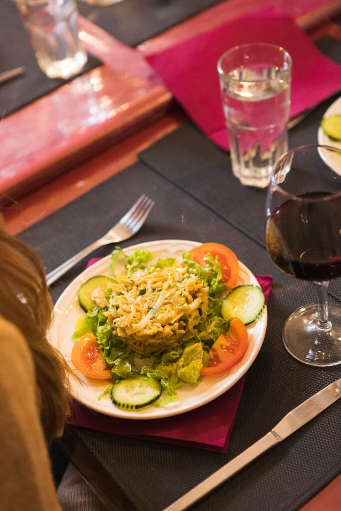 a plate of bacalhau being served with wine on a lisbon food tour