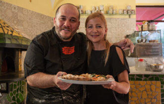 Two people holding a pizza