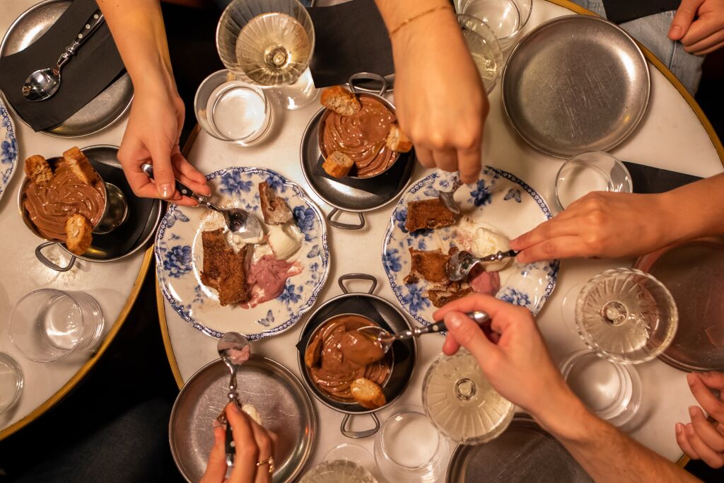 A Barcelona food tour group reaches to share a chocolate mousse dessert