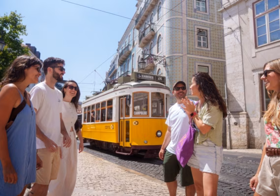 Guests in Lisbon outside with a yellow tram in the background.